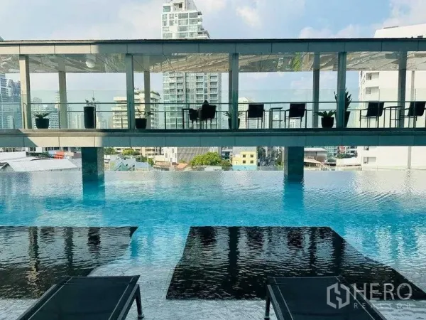 Condominium for rent in Khlong Toei, Bangkok - Infinity-edge swimming pool with loungers and an elevated pavilion overlooking the city.