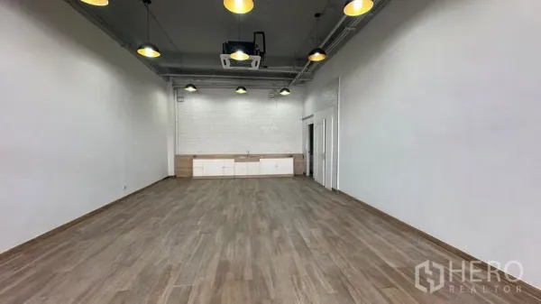 零售空间 出租 - 开放式零售室内，木地板、白色砖墙与内置柜。