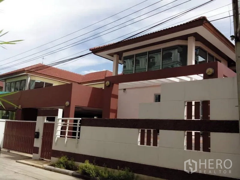 Detached House for rent in Phra Khanong, Bangkok - Modern two-storey detached house with red-tile roof, gated fence, and a covered carport.