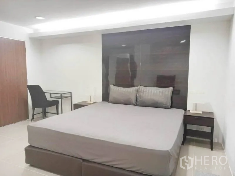 公寓 出租在Khlong Toei, Bangkok - 宽敞卧室配特大床、深色床头板与书桌，配色素雅。