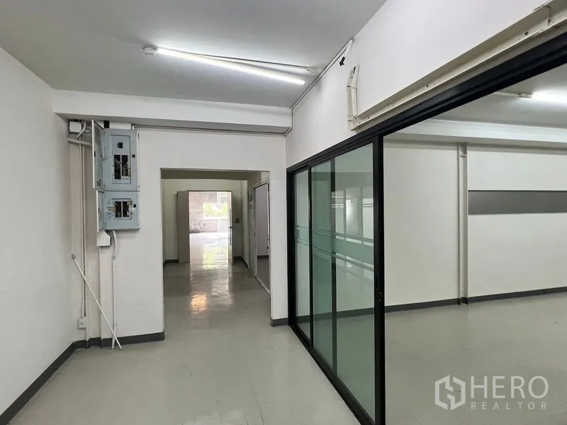 Warehouse for rent in Suan Luang, Bangkok - Corridor with electrical panels and glass sliding doors leading to offices.