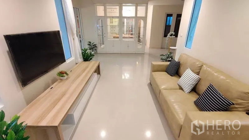 Detached House for rent in Bang Phli, Samut Prakan - Bright living room with beige sofa, wall-mounted TV and built-in cabinet.