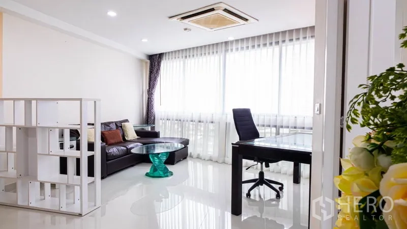 Condominium for rent or sale in Khlong Toei, Bangkok - Home office nook with desk, chair, sofa and bright curtained windows.