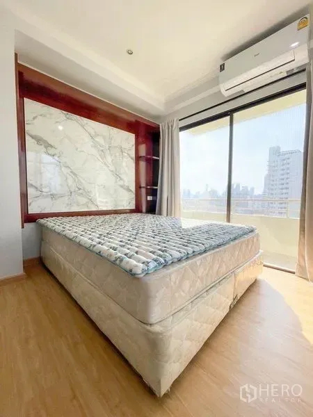 Condominium for rent or sale in Khlong Toei, Bangkok - Second bedroom with marble-style headboard and balcony access to skyline views.