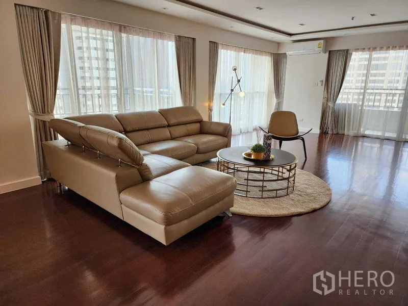 คอนโด ให้เช่าในSathon, Bangkok - ห้องนั่งเล่นสว่าง โซฟาหนังเข้ามุม โต๊ะกลางทรงกลม และหน้าต่างเต็มผนังเห็นวิวเมือง
