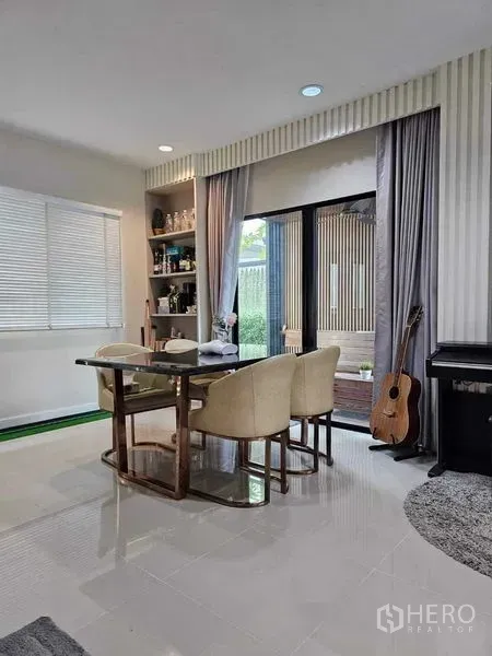 Detached House for sale in Khan Na Yao, Bangkok - Bright dining area with built-in shelving, sliding glass doors to the garden, and a piano.