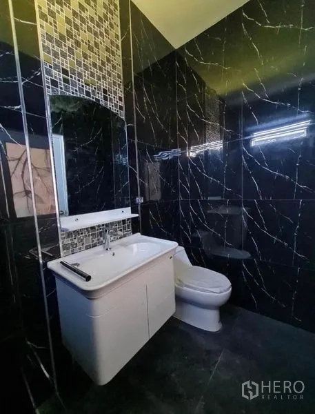 Detached House for sale in Sai Mai, Bangkok - Dark-tone bathroom with mosaic accent strip, vanity, and toilet.