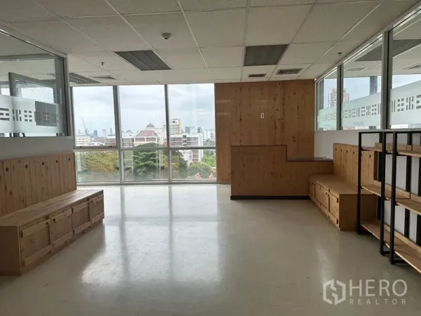 Office Space for rent - Waiting area in the office with wooden benches, shelving and a skyline view through large windows.