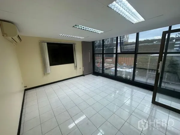 Office Space for rent in Bang Rak, Bangkok - Bright office room with floor-to-ceiling windows, tiled flooring and fluorescent lighting overlooking the city.