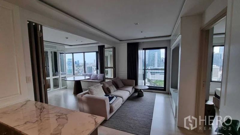 公寓 出售在Pathum Wan, Bangkok - 从厨房望向起居区，沙发、阳台与城市景色