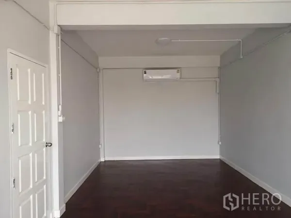 Townhouse for rent or sale in Din Daeng, Bangkok - Spacious room with air conditioner, white walls, and parquet flooring suitable for a bedroom or office.
