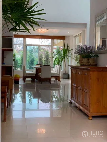 Detached House for rent in Lat Krabang, Bangkok - Hallway leading to the dining space with glossy tiled floors and greenery.
