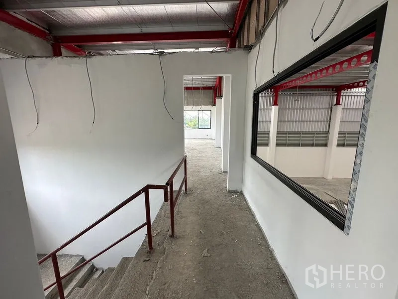Warehouse for rent or sale in Lam Luk Ka, Pathum Thani - Stair corridor with handrail and internal window overlooking the warehouse floor.