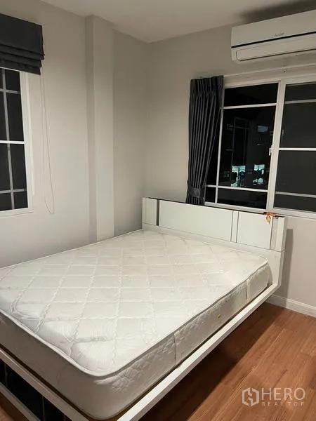 Detached House for rent in Bang Kapi, Bangkok - Corner bedroom with white bed, two windows and air conditioner above.