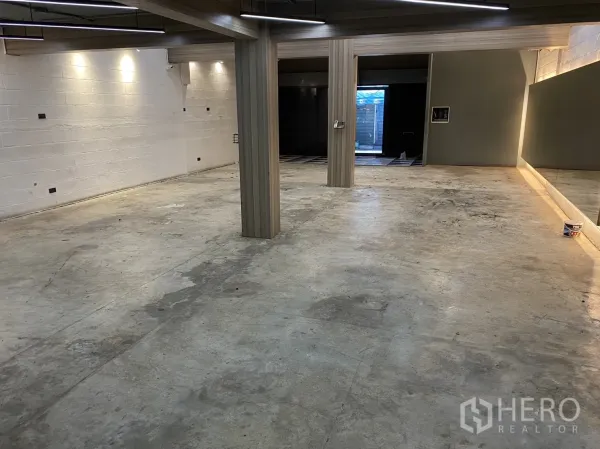 零售空间 出租在Phaya Thai, Bangkok - 宽阔混凝土地面大厅，立柱与线性灯带，带背光镜面通向店门。