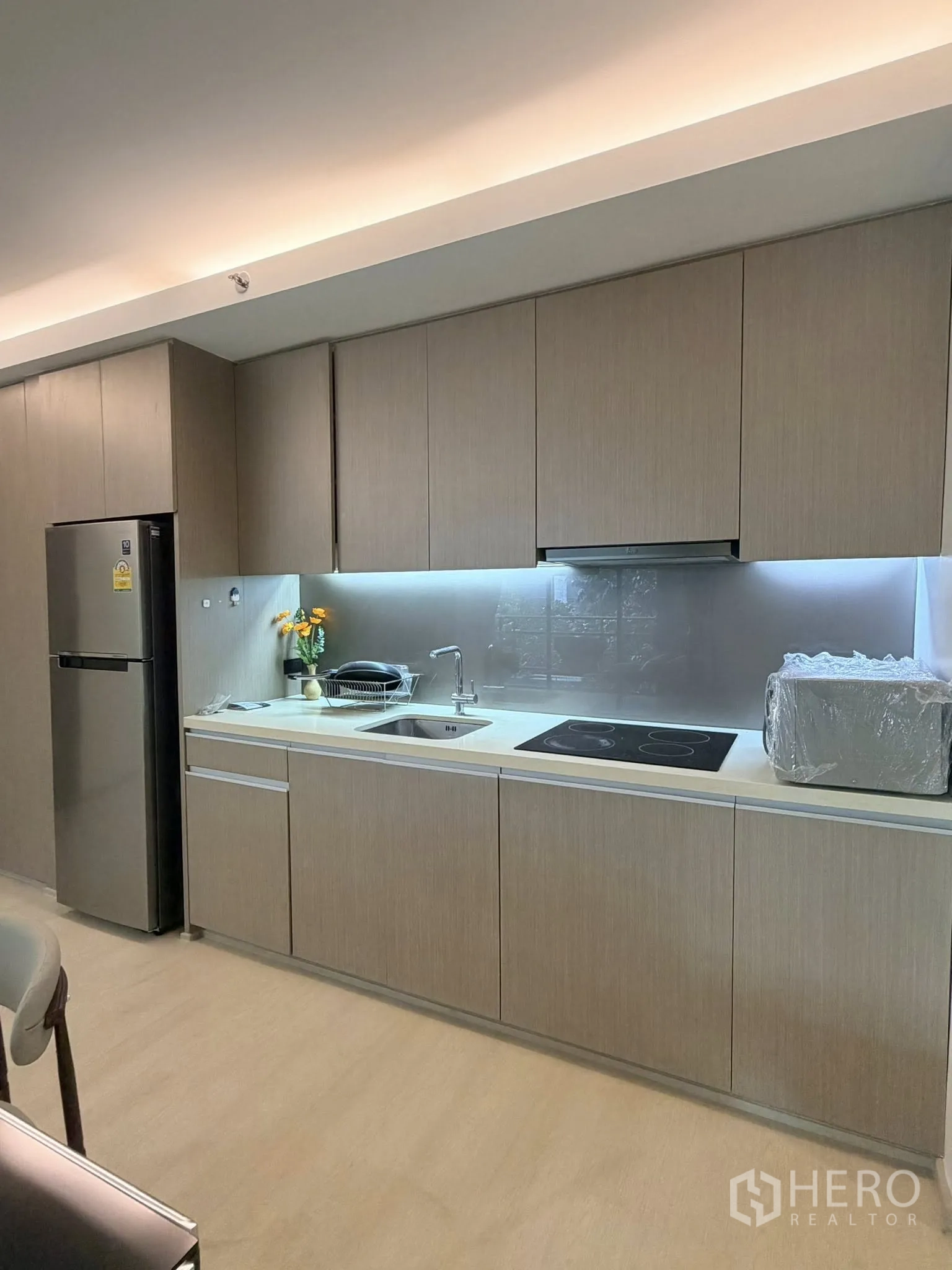 Condominium for rent in Watthana, Bangkok - Sleek kitchenette featuring electric cooktop, sink, and ample storage.