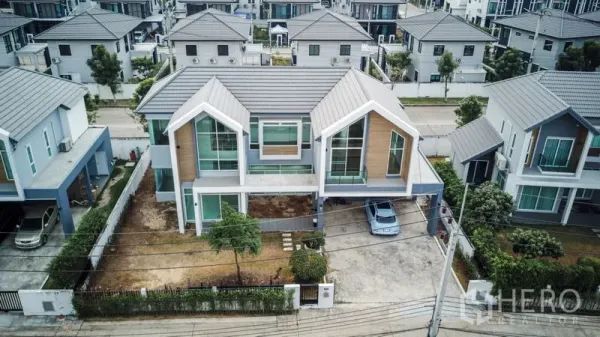 Detached House for rent or sale in Lam Luk Ka, Pathum Thani - Aerial view of a modern two-storey detached house with carport in a gated estate.