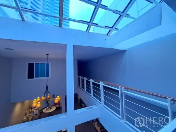 Shophouse for rent in Watthana, Bangkok - Upper-floor corridor beneath a large skylight with metal handrails.