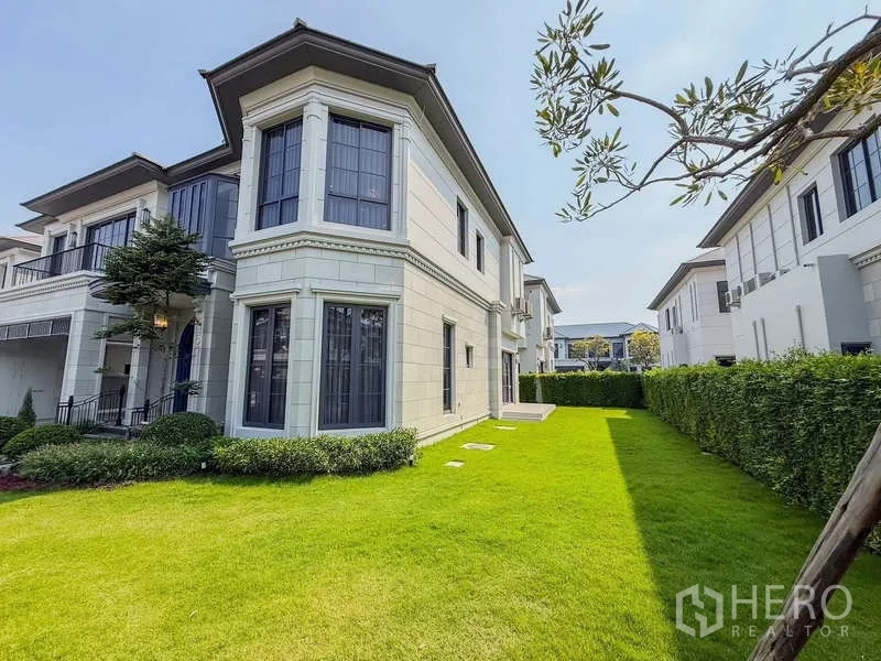 Detached House for rent or sale in Bang Kapi, Bangkok - Side elevation of the house with large bay windows overlooking a green lawn.
