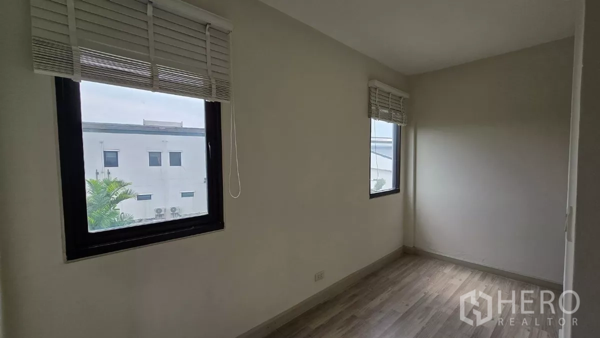 Townhouse for rent or sale in Saphan Sung, Bangkok - Compact bedroom with two corner windows and white blinds.