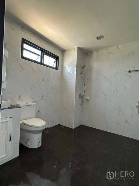 Factory for sale in Khlong Luang, Pathum Thani - Modern bathroom with marble-look wall tiles, shower, toilet and vanity.