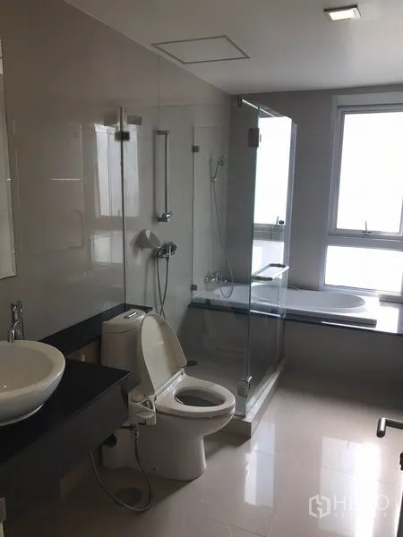 Condominium for rent in Khlong Toei, Bangkok - Main bathroom with glass-enclosed shower, bathtub and window for natural light.