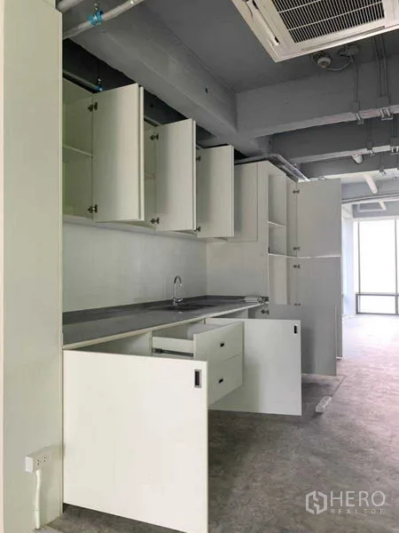 Office Space for rent in Khlong Toei, Bangkok - Office pantry with sink, countertop and multiple white cabinets.