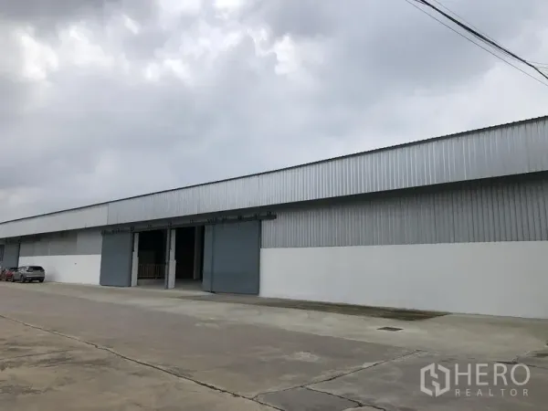 คลังสินค้า ให้เช่าในNonthaburi - ด้านข้างอาคารโกดังผนังเมทัลชีทยาวมีหลายช่องประตูติดกับถนนภายในโครงการ