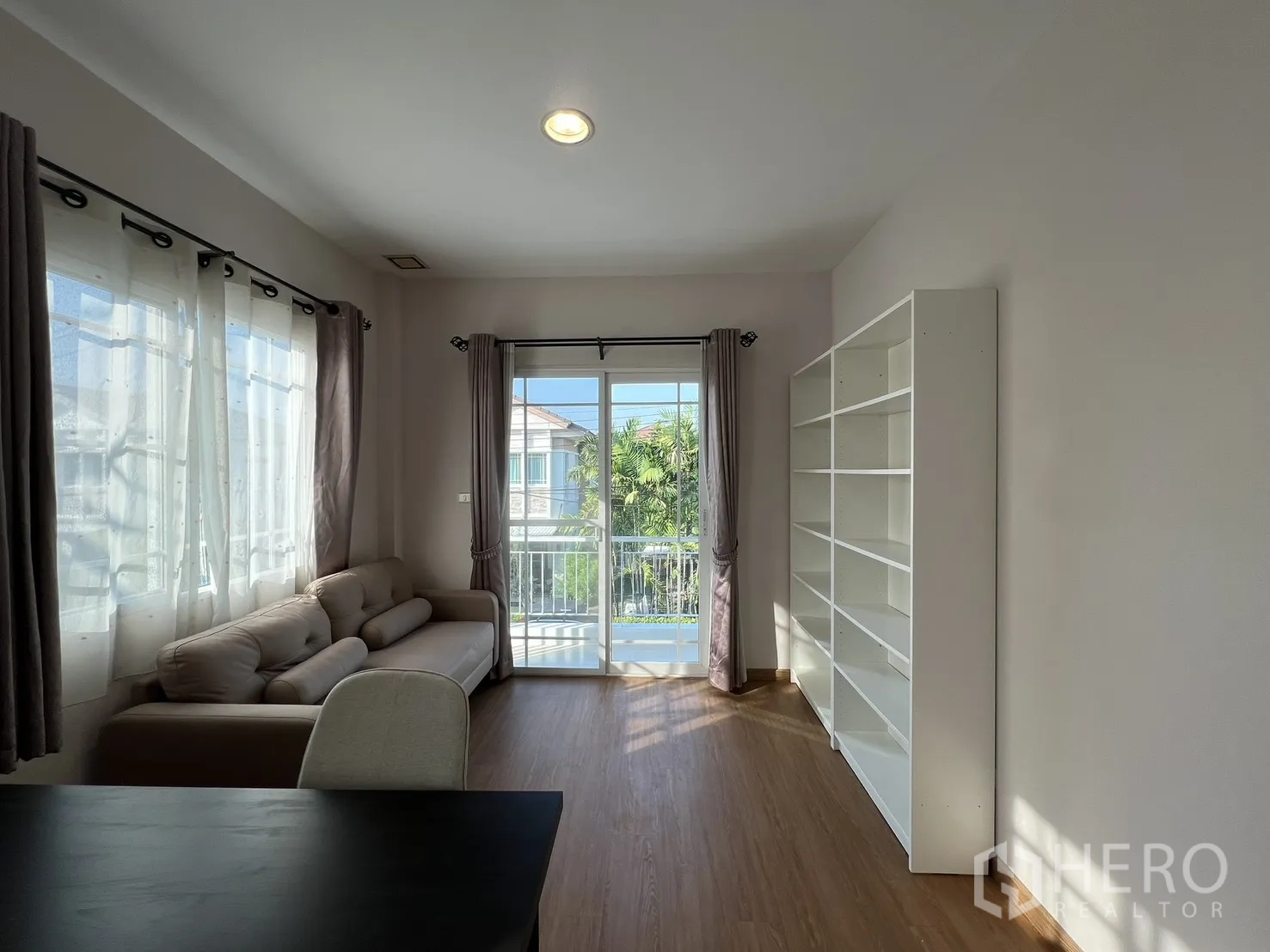 Detached House for rent in Bang Kapi, Bangkok - Family room with shelving and balcony access overlooking the neighborhood.