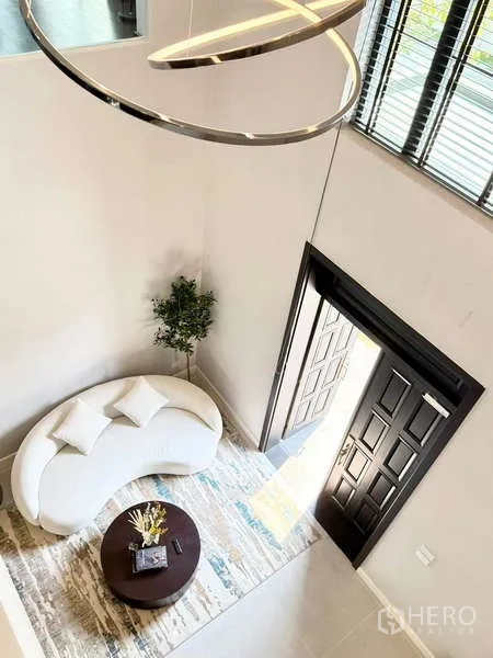 Detached House for rent or sale in Bang Phli, Samut Prakan - Double-height foyer viewed from above with curved white sofa, round coffee table and an open front door.