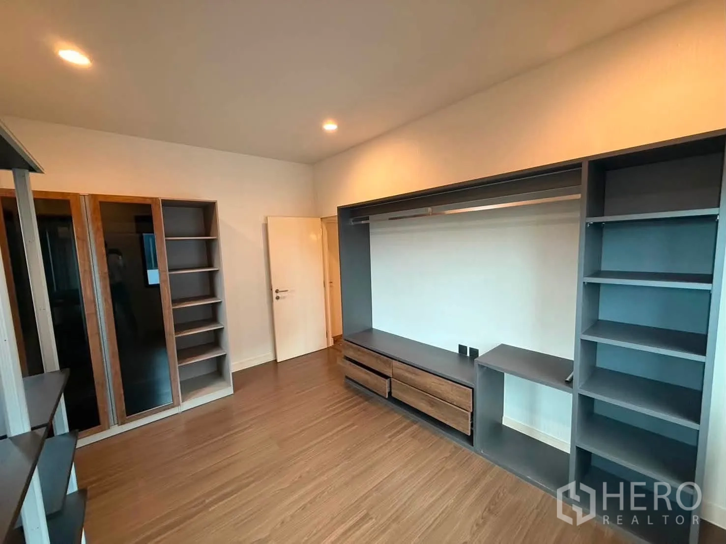 Detached House for rent in Bang Kapi, Bangkok - Walk-in closet room with built-in shelving and drawers on warm wood floors.