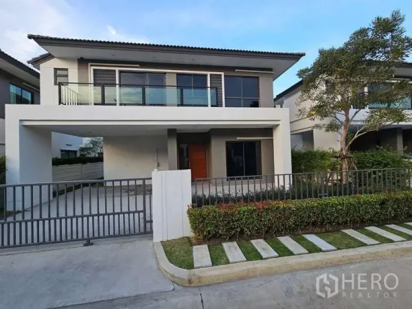 Detached House for rent in Bang Phli, Samut Prakan - Street-facing view of the house facade with landscaped hedge and sliding gate.