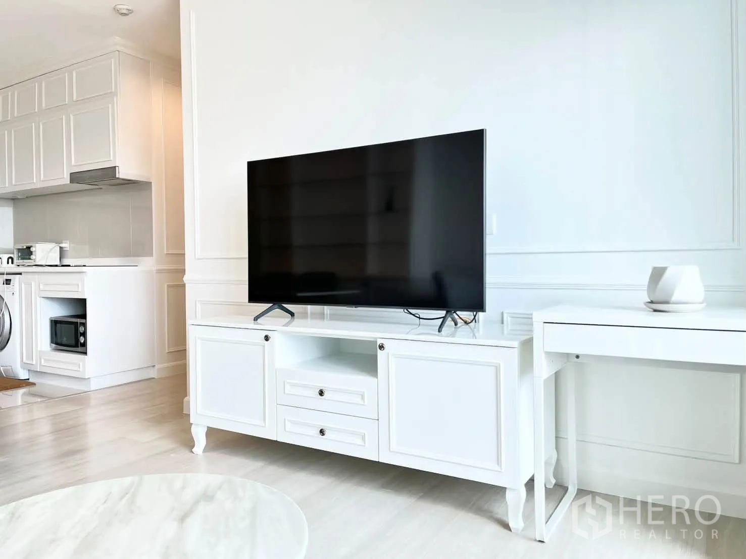 Condominium for rent in Pathum Wan, Bangkok - Living area with TV console and writing desk beside the open kitchen.