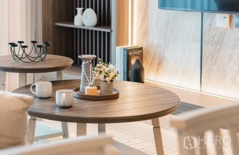Condominium for rent in Watthana, Bangkok - Round coffee tables with decor accents in front of TV feature wall.