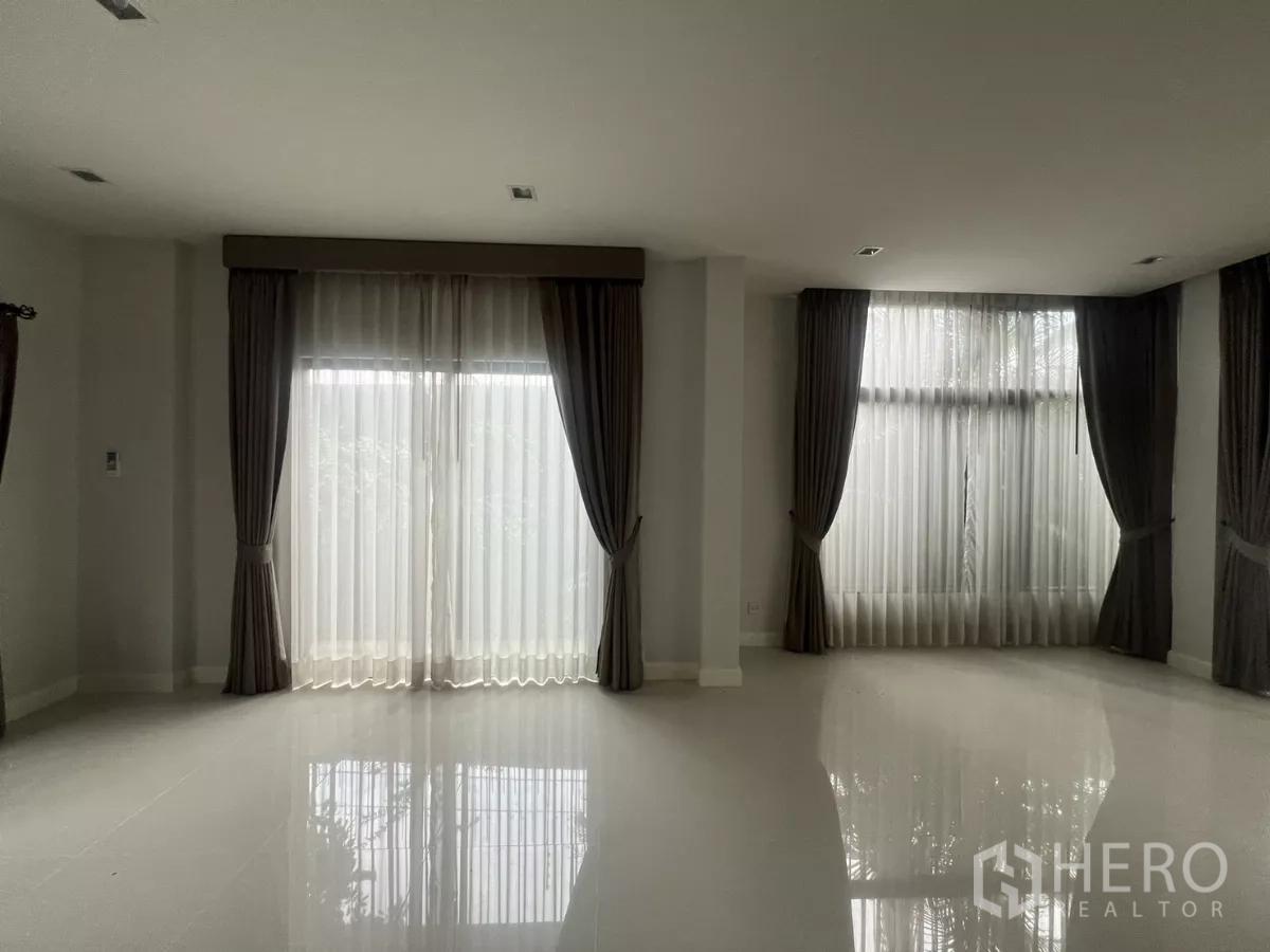 Detached House for sale in Bang Kapi, Bangkok - Spacious living room with large windows and sheer drapes bringing in natural light.