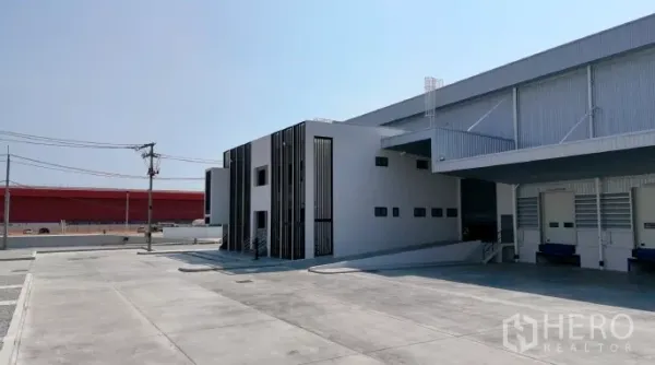 工厂 出租在Samut Prakan - 侧视图，带坡道连接仓库与办公区，周边混凝土作业场适合卡车通行