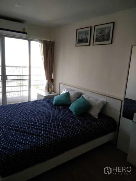 Condominium for rent in Khlong Toei, Bangkok - Bedroom with sliding glass doors to the balcony and city view, filled with natural light.