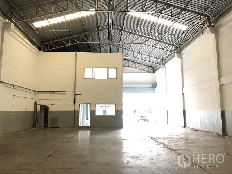 工厂 出租在Pathum Thani - 仓库内部，可见夹层办公室与大型装卸卷门。