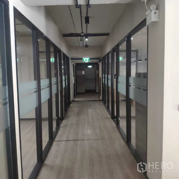 Office Space for rent - Glass-walled corridor with exit signs and exposed ceiling services.
