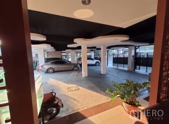 สำนักงานที่บ้าน ให้เช่า - ที่จอดรถชั้นล่างแบบมีหลังคา เสากลมหลายต้น และประตูรั้วรักษาความปลอดภัยของอาคารโฮมออฟฟิศ