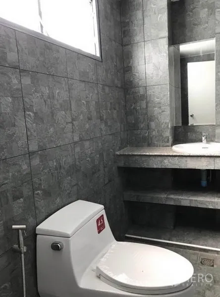 Townhouse for rent in Suan Luang, Bangkok - Bathroom with gray stone tiles, a window, built-in vanity and toilet.