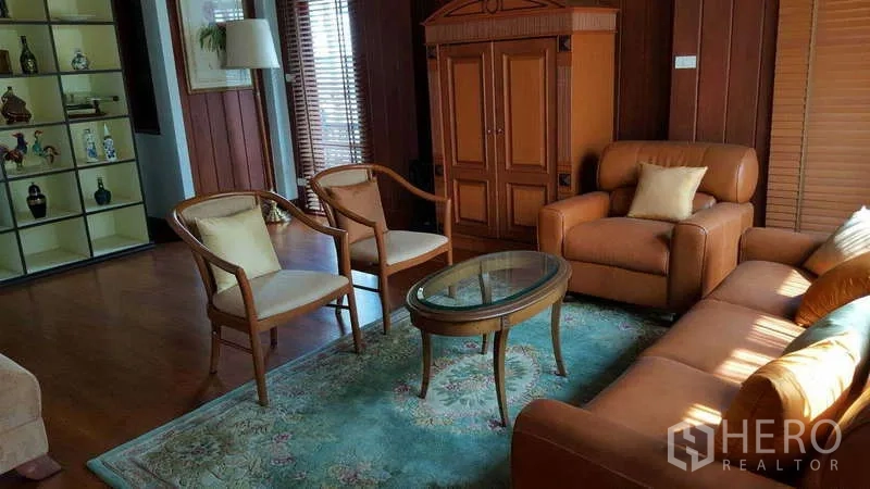 联排别墅 出租在Khlong Toei, Bangkok - 客厅配皮沙发、扶手椅与展示柜