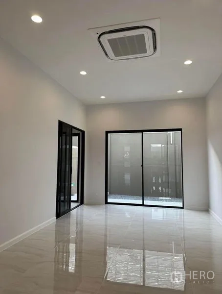 Townhouse for rent in Yan Nawa, Bangkok - Bright multi-purpose room with ceiling cassette air conditioner and black-framed sliding doors.