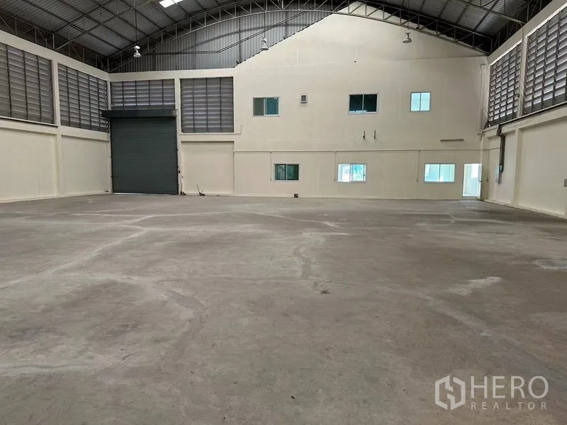 Warehouse for rent in Mueang Samut Sakhon, Samut Sakhon - Warehouse bay with large roller shutter door and attached two-storey office block with windows.