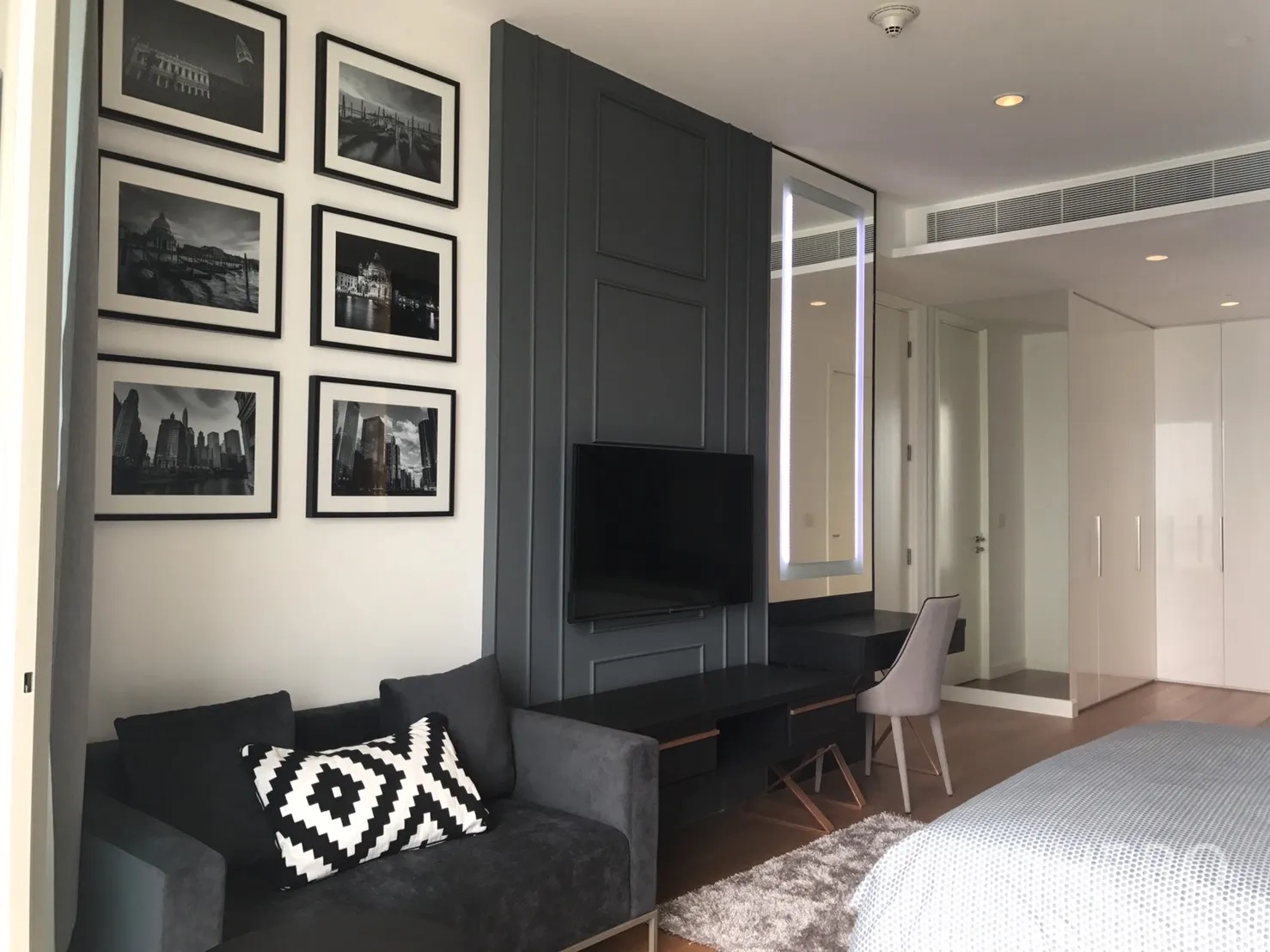 Condominium for rent in Pathum Wan, Bangkok - Bedroom corner with framed wall art, mounted TV and compact sofa.