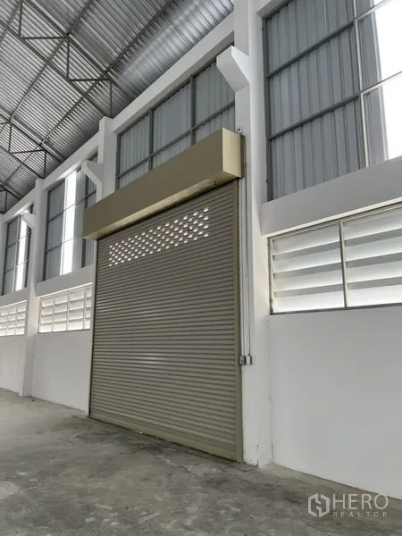 工厂 出租或出售在Bang Bo, Samut Prakan - 室内卷帘门特写，旁侧设有通风百叶窗。