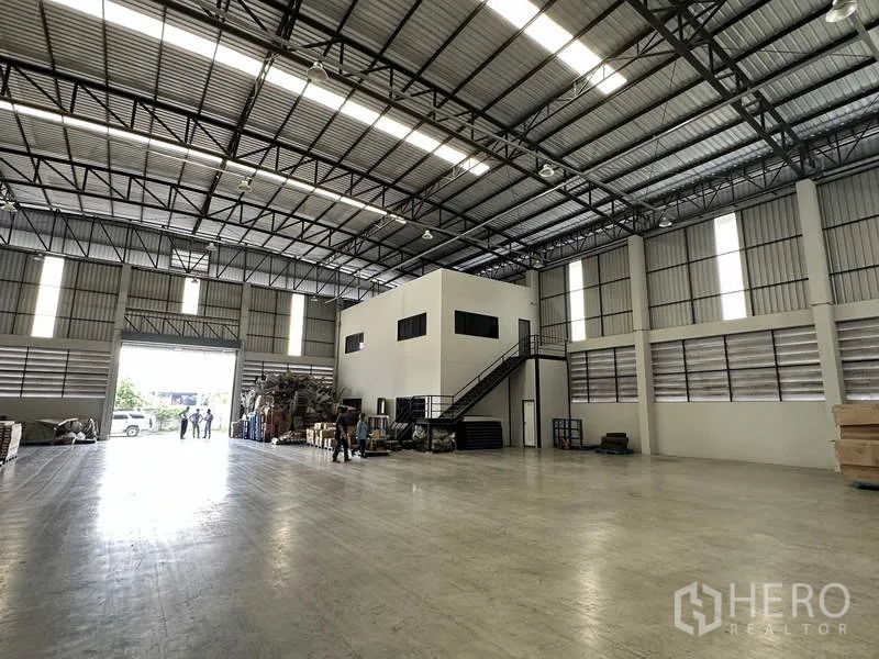 Warehouse for rent in Bang Phli, Samut Prakan - Warehouse hall featuring a two-storey internal office, staircase and a large loading door opening to the driveway.