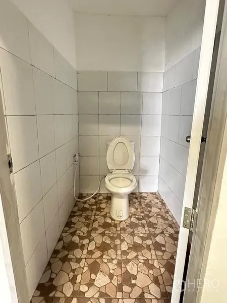 Warehouse for rent in Khan Na Yao, Bangkok - Clean tiled restroom with western toilet and handheld bidet spray.