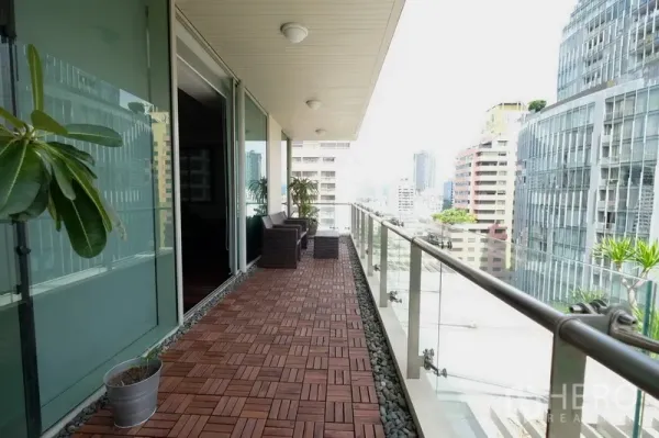 Condominium for rent in Bang Rak, Bangkok - Long glass‑railed balcony with outdoor chairs and potted plants facing modern towers in Silom.