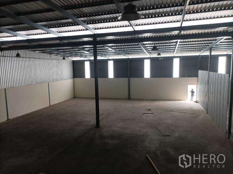 工厂 for rent in Ban Phaeo, Samut Sakhon - 宽敞仓库空间，墙面竖向采光窗与侧门可见。